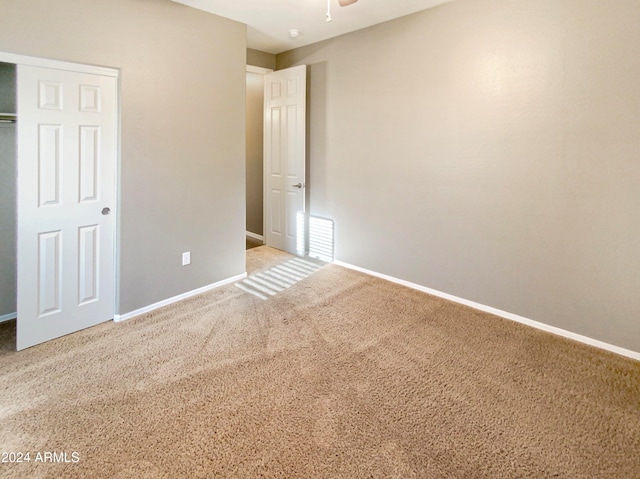 unfurnished bedroom featuring light colored carpet and a closet