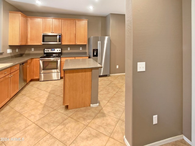 kitchen with a kitchen island, light tile patterned flooring, and stainless steel appliances