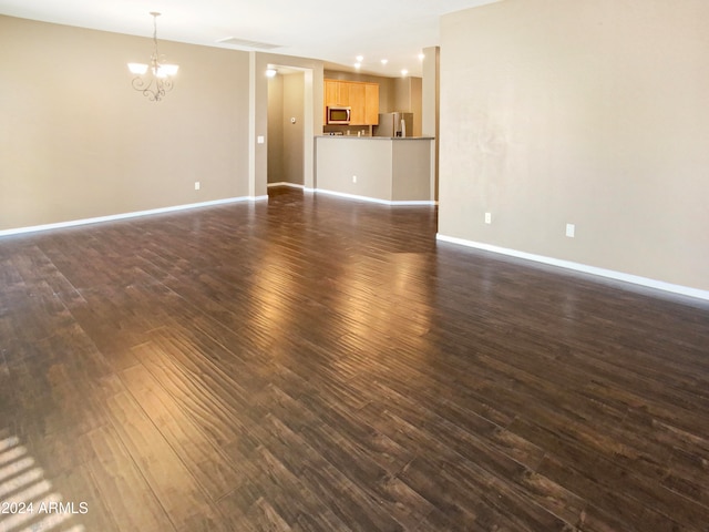 unfurnished living room with dark hardwood / wood-style floors and an inviting chandelier