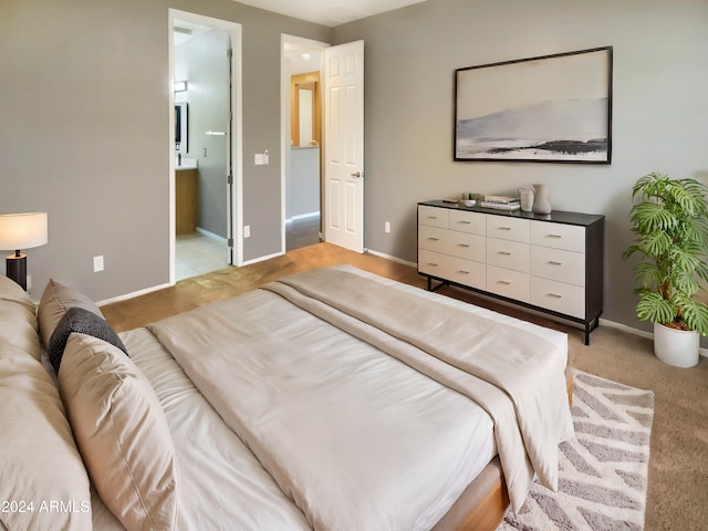 bedroom with ensuite bathroom and light carpet