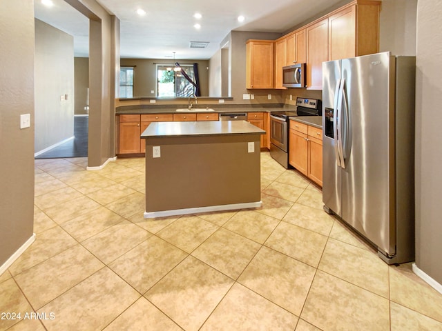 kitchen featuring sink, a kitchen island, light tile patterned floors, and appliances with stainless steel finishes