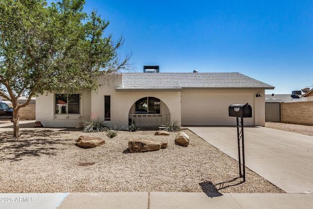 ranch-style home with driveway, fence, stucco siding, and a garage