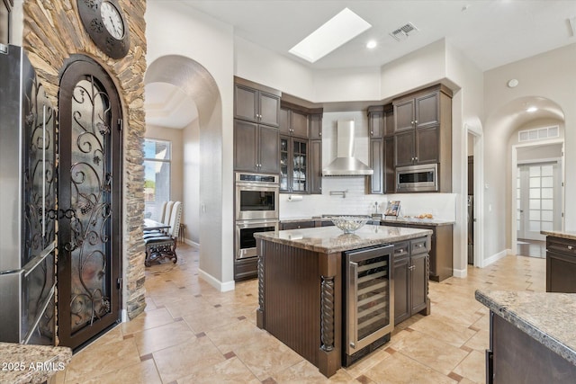 34096 N 87th Way, Scottsdale, AZ 85266 - kitchen featuring wine cooler, visible vents, wall chimney range hood, arched walkways, and appliances with stainless steel finishes