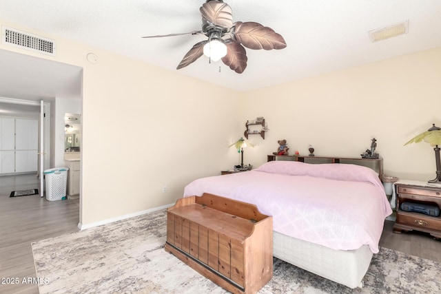 bedroom with wood finished floors, visible vents, and baseboards