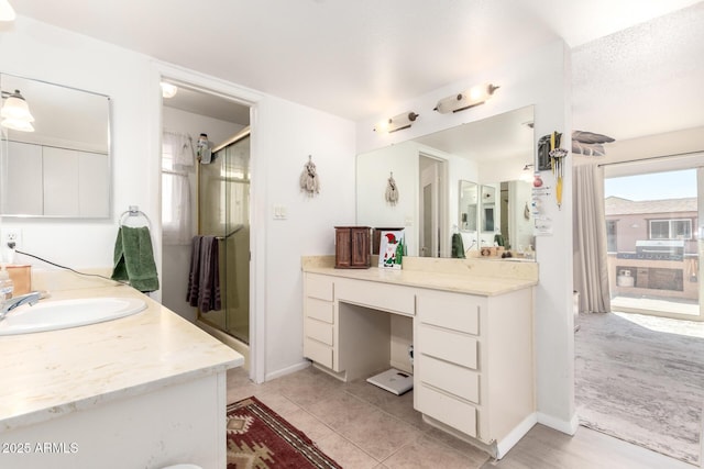 bathroom with tile patterned flooring, a shower stall, vanity, and baseboards