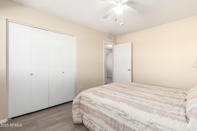 bedroom with visible vents, a textured ceiling, a closet, and wood finished floors