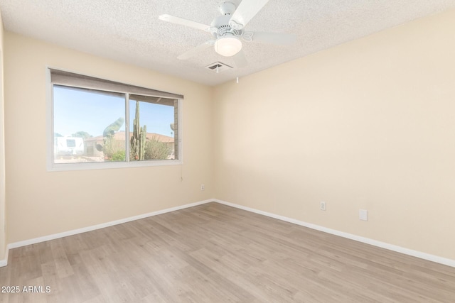 unfurnished room with baseboards, visible vents, light wood finished floors, and a textured ceiling