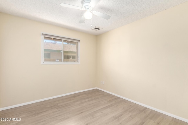 spare room featuring visible vents, baseboards, light wood-style floors, a textured ceiling, and a ceiling fan