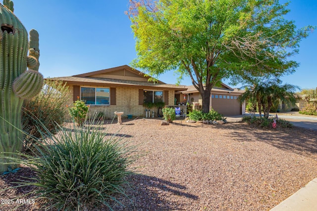 ranch-style home featuring driveway, brick siding, and an attached garage