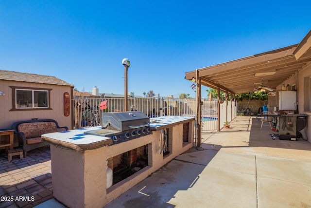 view of patio with ceiling fan, a grill, an outdoor kitchen, and fence