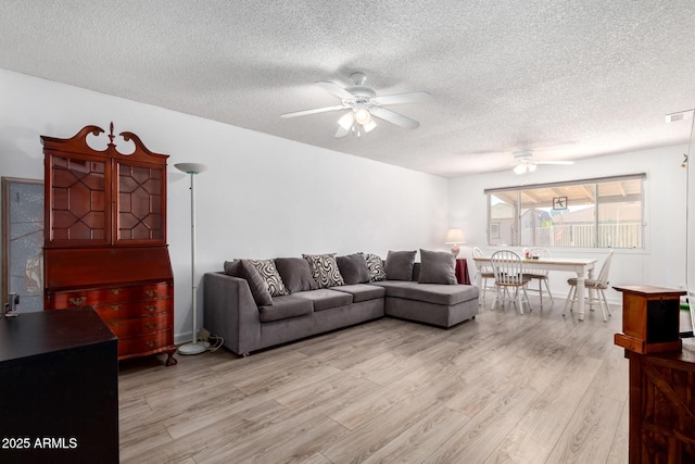 living area with visible vents, a textured ceiling, light wood-type flooring, and a ceiling fan