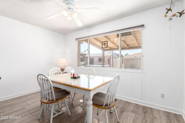 dining space with ceiling fan, wood finished floors, baseboards, and a textured ceiling