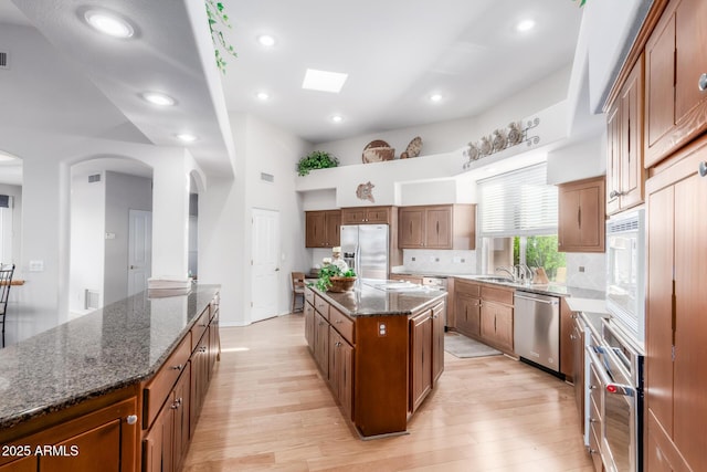 24801 N Vado Ct, Rio Verde, AZ 85263 - kitchen featuring stainless steel appliances, arched walkways, a center island, light wood-type flooring, and recessed lighting