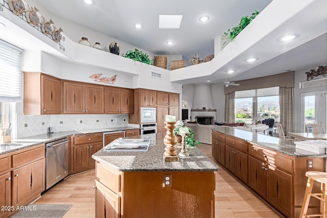 24801 N Vado Ct, Rio Verde, AZ 85263 - kitchen featuring appliances with stainless steel finishes, a spacious island, light wood-type flooring, brown cabinets, and recessed lighting