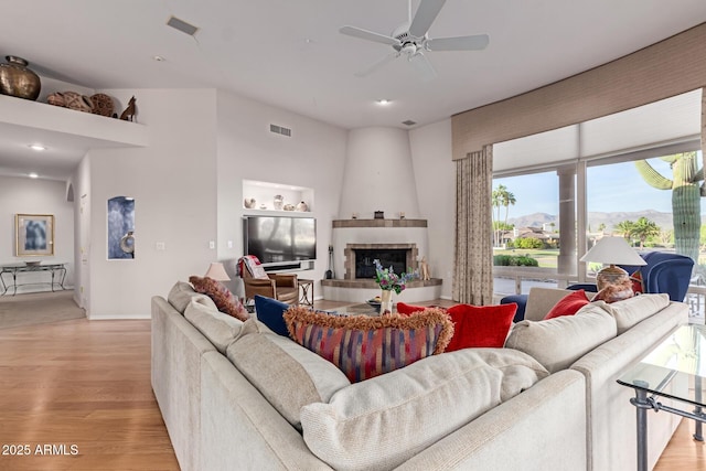 24801 N Vado Ct, Rio Verde, AZ 85263 - living area with light wood-style flooring, a tiled fireplace, ceiling fan, and baseboards