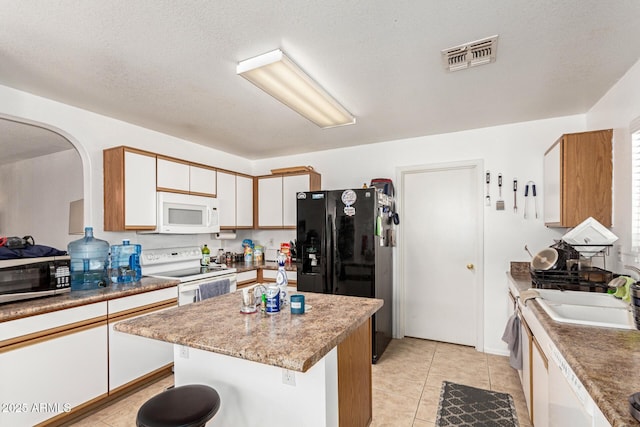 2202 S Lawther Dr, Apache Junction, AZ 85120 - kitchen featuring white appliances, light tile patterned floors, a center island, white cabinets, and arched walkways