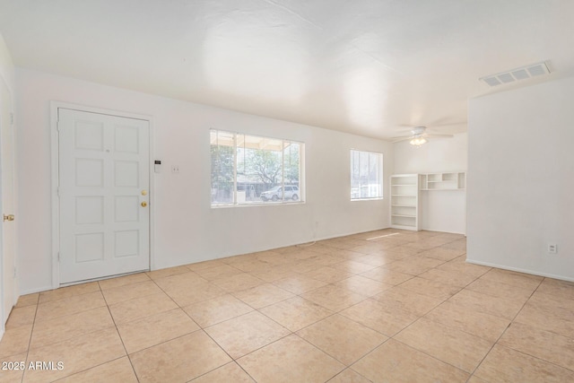 empty room featuring light tile patterned floors, visible vents, and ceiling fan