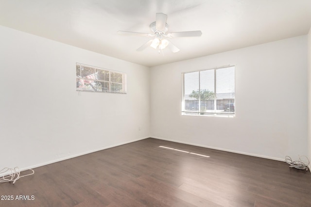 empty room with baseboards, dark wood-type flooring, and ceiling fan