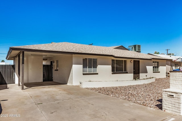 back of property with brick siding, an attached carport, driveway, and a shingled roof