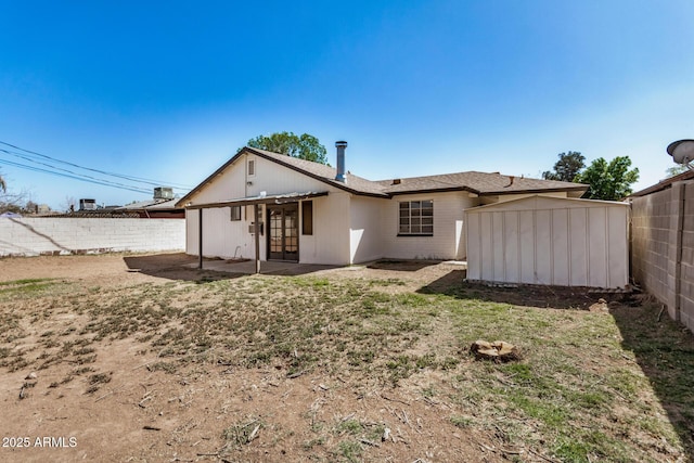 rear view of house featuring french doors, a storage shed, an outdoor structure, a fenced backyard, and a patio