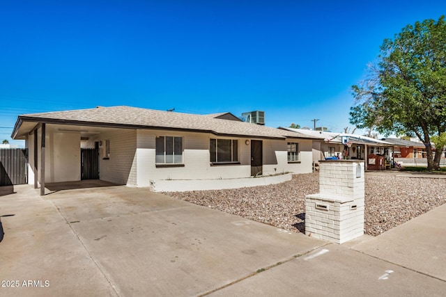 single story home featuring an attached carport, concrete driveway, brick siding, and roof with shingles