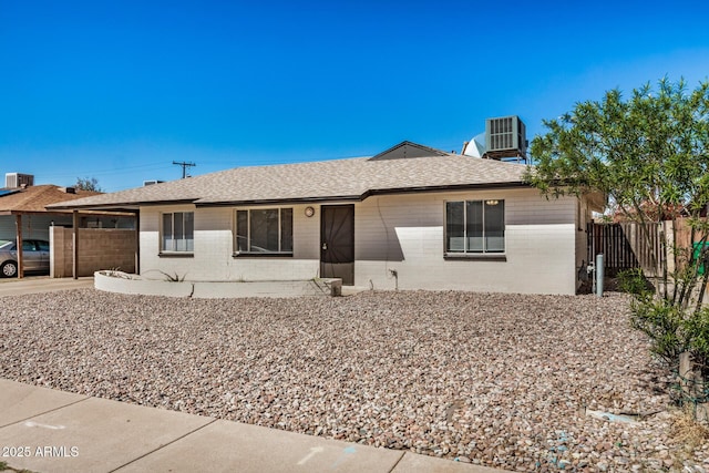 view of front facade featuring driveway, central AC, fence, a garage, and brick siding