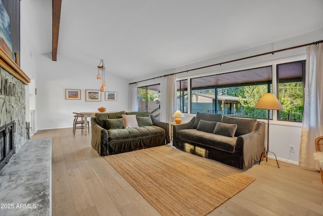 living area featuring a fireplace, hardwood / wood-style floors, vaulted ceiling with beams, and baseboards
