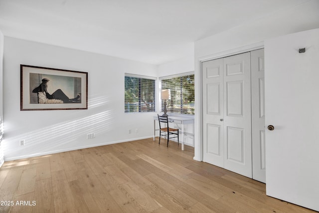 unfurnished bedroom featuring a closet, baseboards, and light wood-style floors