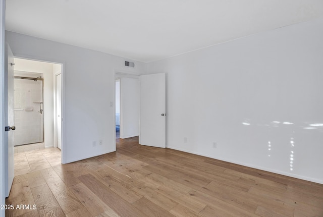 spare room featuring visible vents, light wood-style flooring, and baseboards