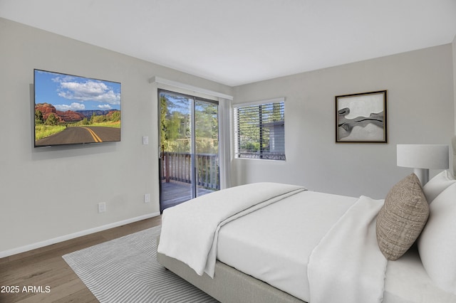 bedroom with wood finished floors, access to outside, and baseboards