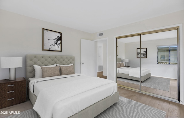 bedroom featuring a closet, visible vents, and wood finished floors