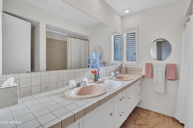 full bathroom featuring tile patterned floors, baseboards, double vanity, and a sink