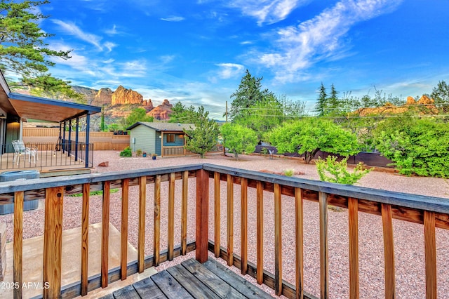 wooden deck with an outdoor structure, central air condition unit, and a fenced backyard