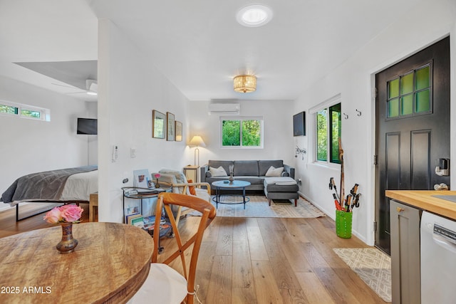 interior space featuring a healthy amount of sunlight, light wood-type flooring, a wall mounted AC, and baseboards