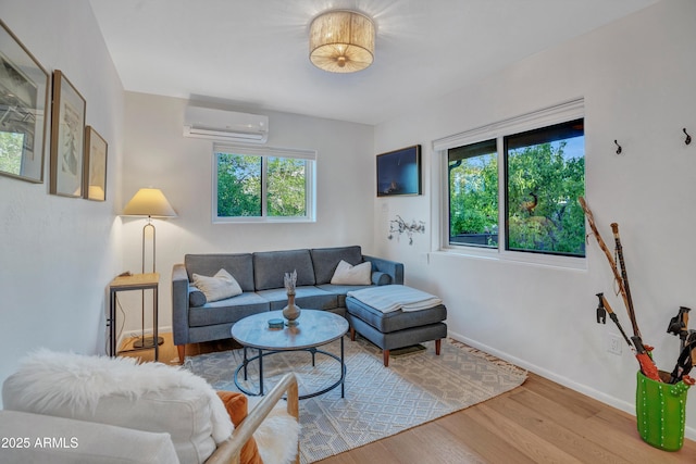 living room featuring baseboards, a wall unit AC, and wood finished floors