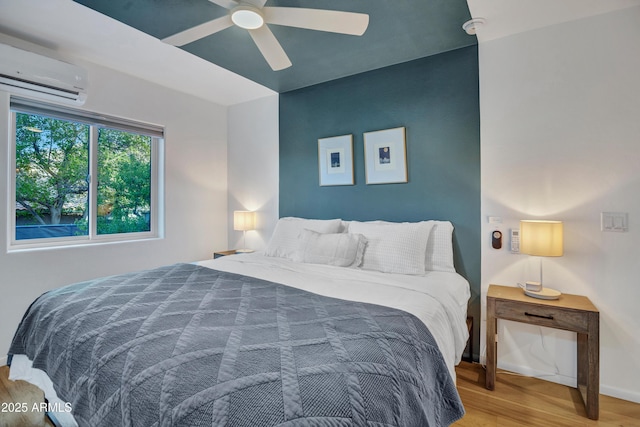 bedroom with baseboards, wood finished floors, a ceiling fan, and an AC wall unit