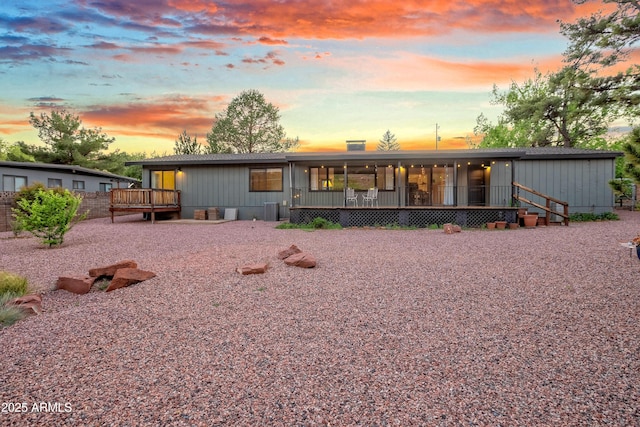 back of property at dusk featuring central AC and a wooden deck