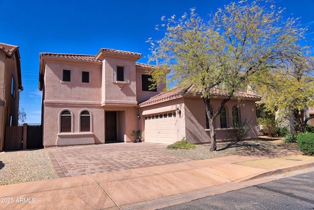 mediterranean / spanish-style house featuring driveway, a tile roof, an attached garage, fence, and stucco siding