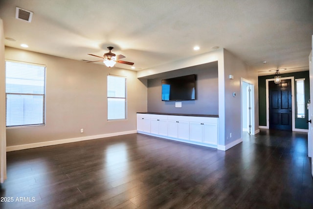 unfurnished living room featuring dark wood-style floors, visible vents, ceiling fan, and baseboards