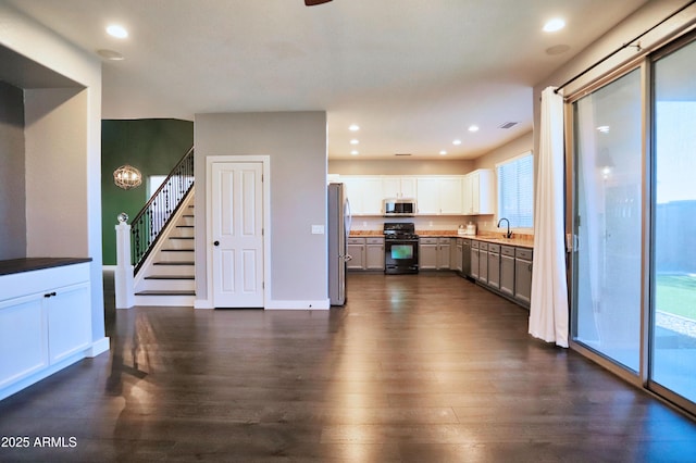 kitchen featuring white cabinets, dark wood-style floors, stainless steel appliances, a sink, and recessed lighting