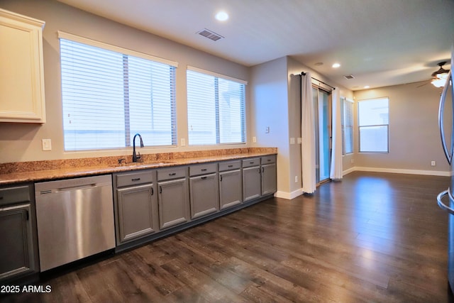 kitchen with visible vents, dark wood-style floors, gray cabinetry, stainless steel dishwasher, and a sink