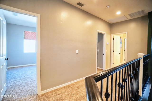 hall featuring carpet, visible vents, and baseboards