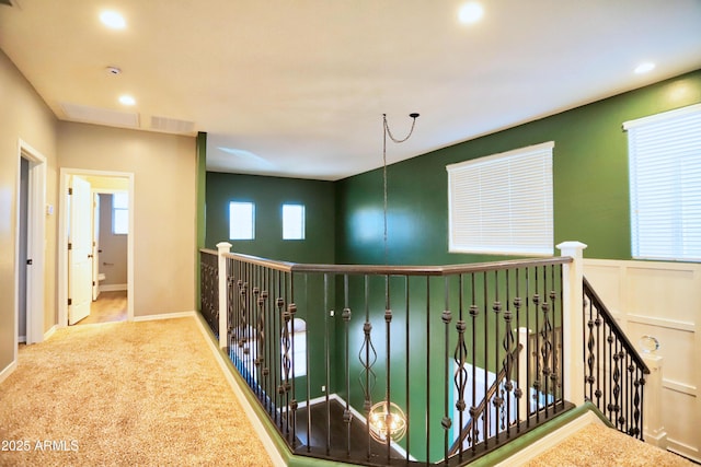 hallway with a decorative wall, a wainscoted wall, recessed lighting, carpet flooring, and an upstairs landing