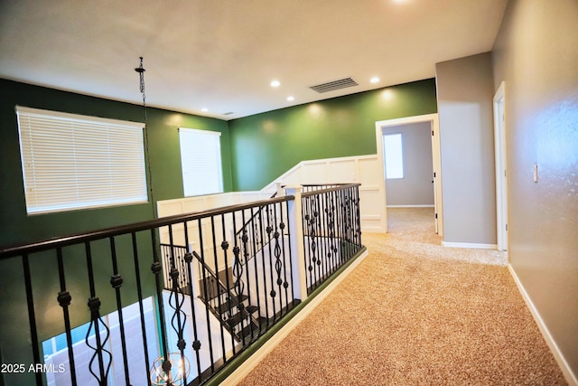 hall with recessed lighting, light colored carpet, visible vents, an upstairs landing, and baseboards