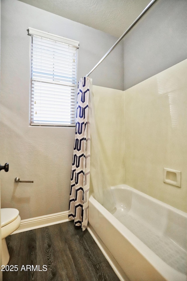 full bathroom with baseboards, toilet, wood finished floors, shower / bathtub combination with curtain, and a textured ceiling