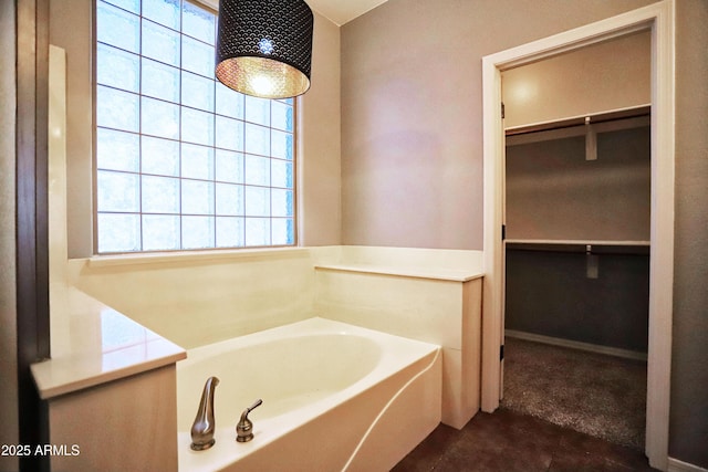 bathroom featuring a spacious closet and a bath