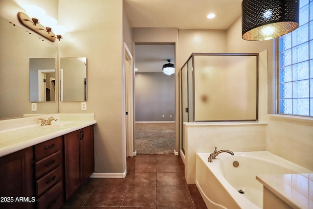 bathroom with a garden tub, a stall shower, vanity, baseboards, and tile patterned floors