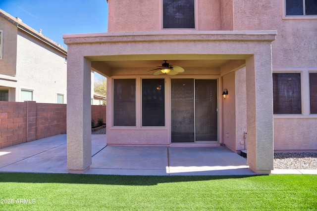 view of exterior entry with ceiling fan, a patio, fence, and stucco siding