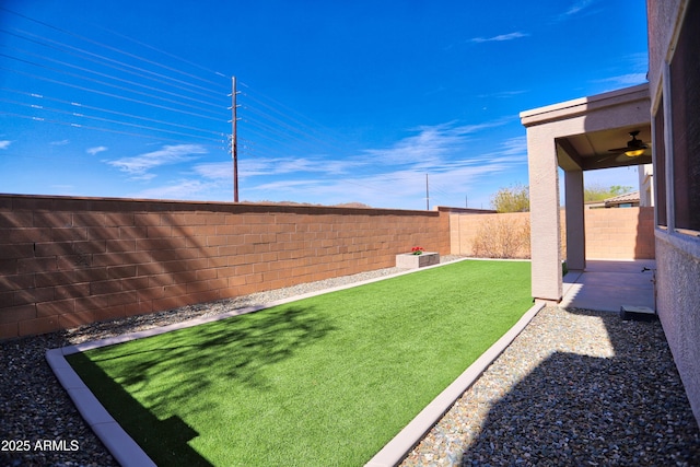 view of yard with a fenced backyard and a ceiling fan