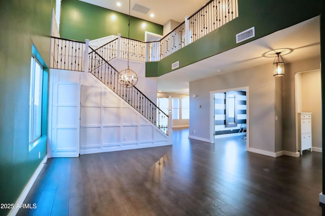 unfurnished living room with dark wood-style floors, a chandelier, visible vents, and stairway